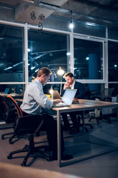 Dos caballeros se quedan despiertos hasta tarde en la oficina trabajando . — Foto de Stock
