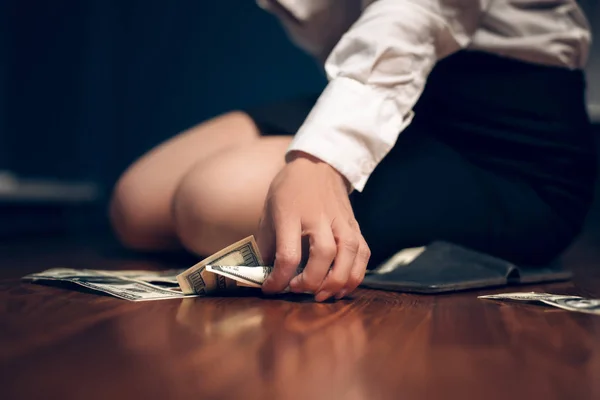 Business woman sitting on table with pile of dollar bills. — Stock Photo, Image