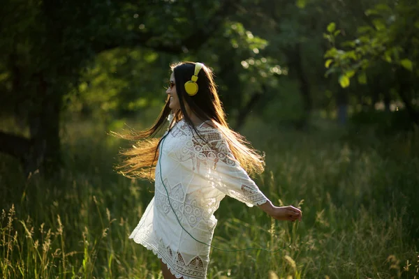 Flicka med hörlurar som dansar i fältet. — Stockfoto