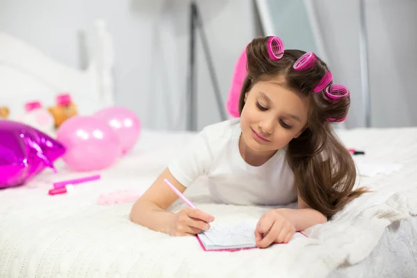 Gadis menulis di buku catatannya di tempat tidur . — Stok Foto