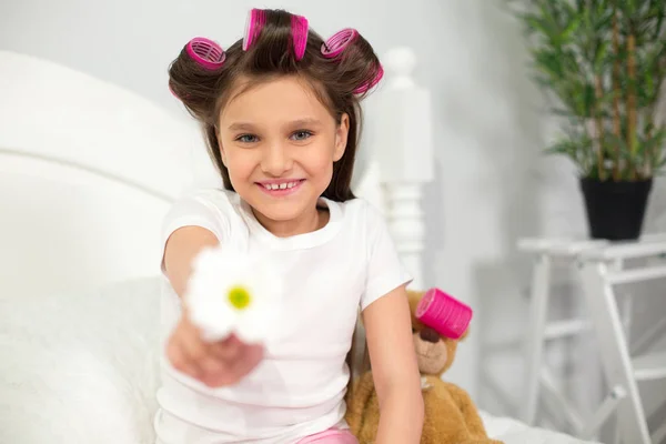 Young girl sitting on her bed with flower. — Stock Photo, Image