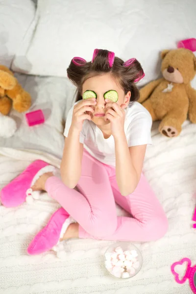 Petite fille avec des tranches de concombre sur les yeux . — Photo