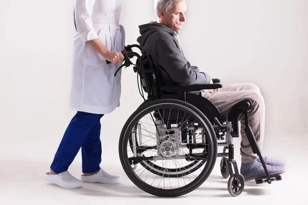 Nurse pushing wheelchair with man in it.