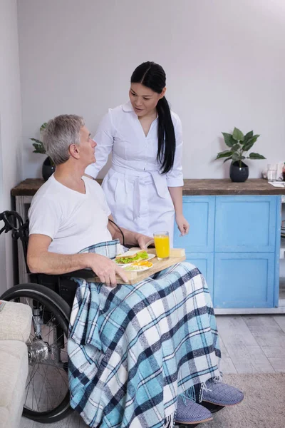 Hemşire hasta tekerlekli sandalyede yiyecek getirmek. — Stok fotoğraf