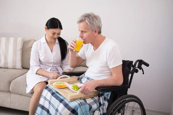 Infirmière apportant de la nourriture au patient en fauteuil roulant . — Photo