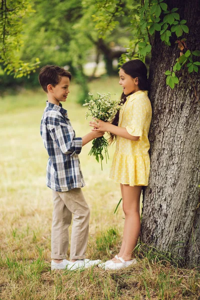 Mały chłopiec dając kwiaty na kwiaty dziewczyna. — Zdjęcie stockowe