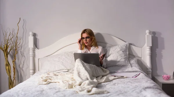 Yatakta oturmuş işkadını dizüstü bilgisayar kullanarak — Stok fotoğraf