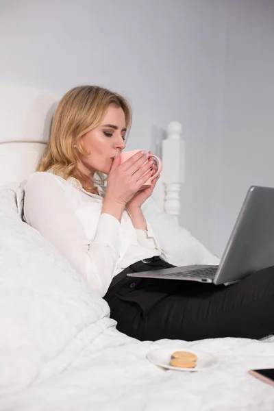 女はベッドに座ってコーヒーを楽しみます ベッドのコンセプトのビジネス 白い背景に分離 — ストック写真
