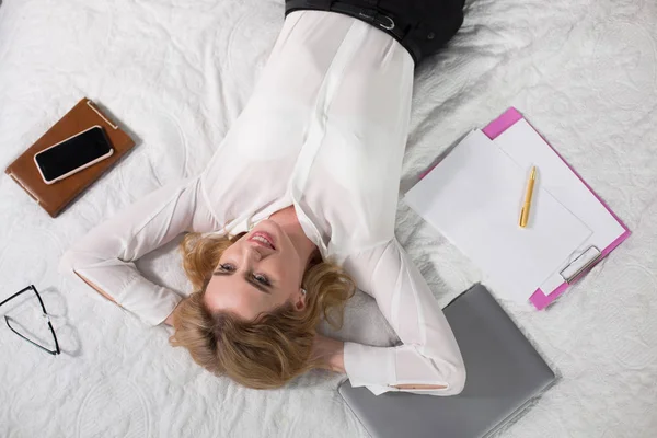 Leende ung affärskvinna liggande på sängen — Stockfoto