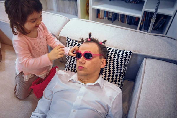 Cute little girl apply lipstick to father while he is sleeping — Stock Photo, Image