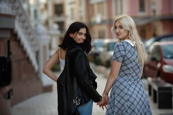 Girlfriends holding hands and walking — Stock Photo, Image