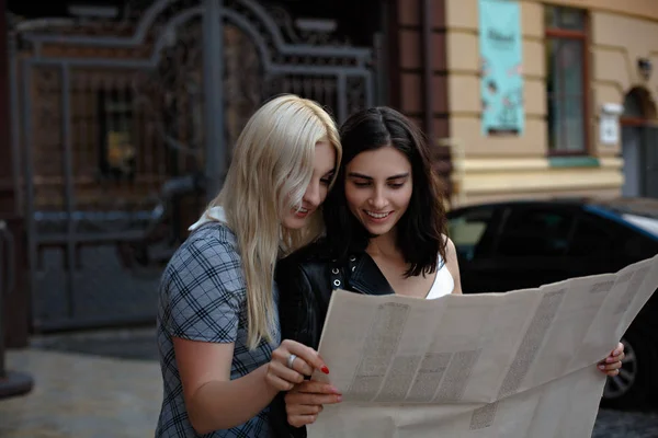 Deux charmantes femmes gaies marchent avec la carte — Photo