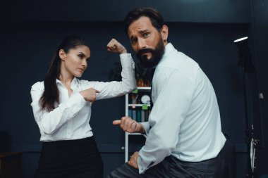 Business people showing muscles in office clipart