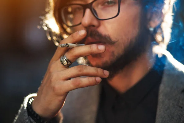 Ένας άντρας με μακριά μαλλιά που καπνίζει έξω από — Φωτογραφία Αρχείου