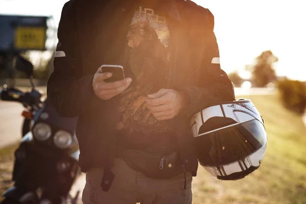 Tutup tampilan tangan pengendara motor menggunakan smartphone-nya — Stok Foto