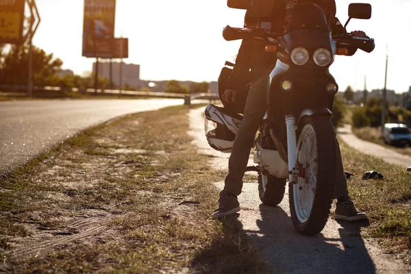 Vista de cerca del motociclista sentado en la motocicleta en un camino vacío en un día soleado —  Fotos de Stock