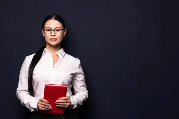 Mujer de negocios sonriente sosteniendo cuaderno rojo —  Fotos de Stock