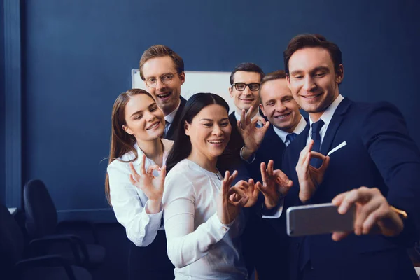 Smilende forretningsfolk poserer for selfie - Stock-foto