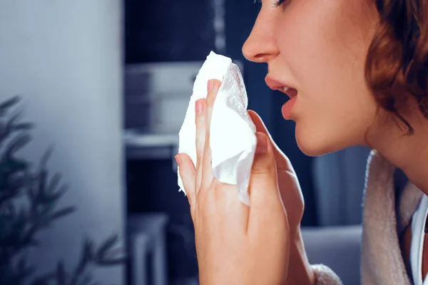 Sick woman holds white handkerchieif while sneezing — Stock Photo, Image