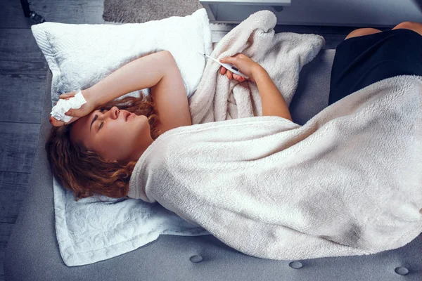 Больной женщины в постели с термометром — стоковое фото
