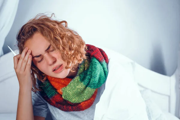 Sick blonde girl is scarf touches her head. In bed — Stock Photo, Image