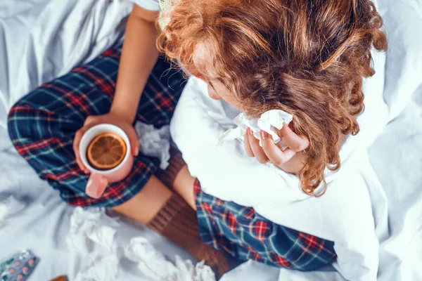 Vista desde arriba mujer enferma en la cama sosteniendo una taza de té con naranja en ella —  Fotos de Stock