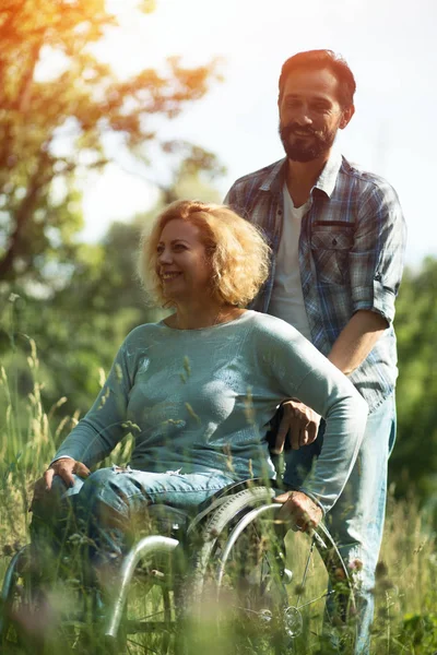 Mutlu kadın kocası ile tekerlekli sandalyede. Açık havada — Stok fotoğraf