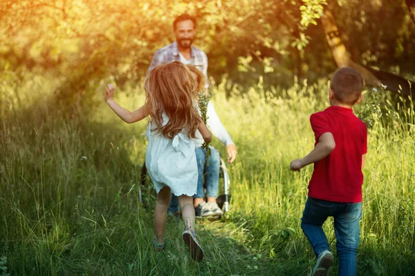 Kinder rennen zu ihrer behinderten Mutter in den Park — Stockfoto