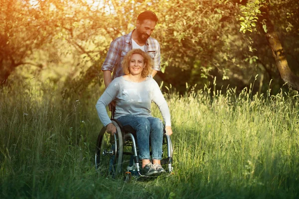 Tekerlekli sandalyede gülümseyen kadın koca güneşli parkta — Stok fotoğraf