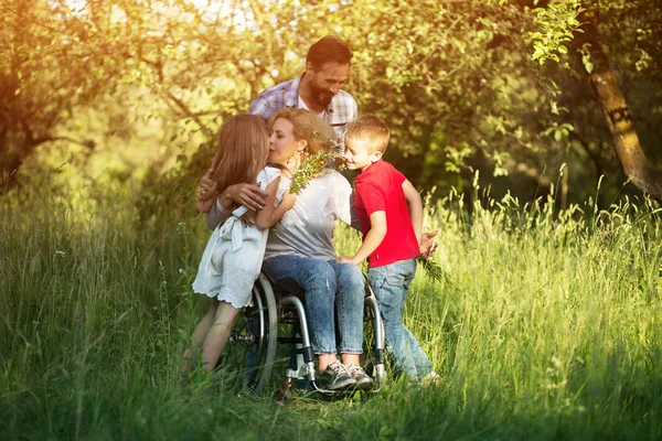 Vrouw in rolstoel kussen haar zoon onder familieleden — Stockfoto