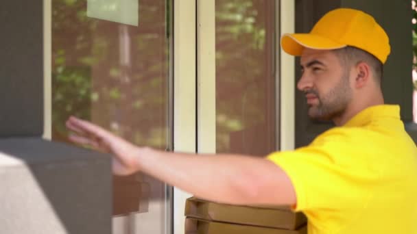 Correio em uniforme amarelo entrega caixas de pizza para mulher à porta . — Vídeo de Stock