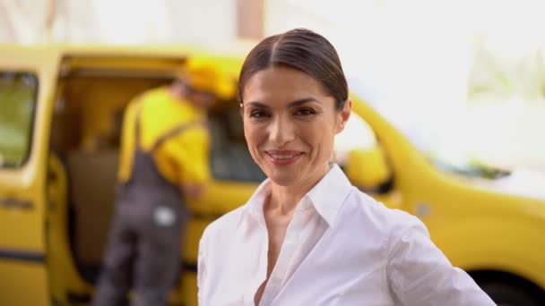 Die lächelnde Geschäftsfrau zeigt den Daumen nach oben. Verschwommener Lieferwagen und Kurier im Hintergrund — Stockvideo