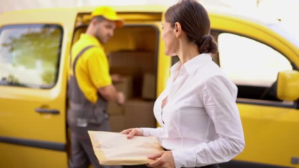 Alegre entrega hombre toma un paquete de la joven mujer — Vídeos de Stock