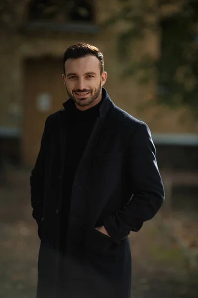 Красивый улыбчивый мужчина в черном пальто — стоковое фото