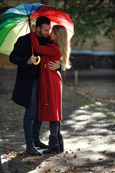 Junge Leute spazieren im Park unter buntem Regenschirm — Stockfoto