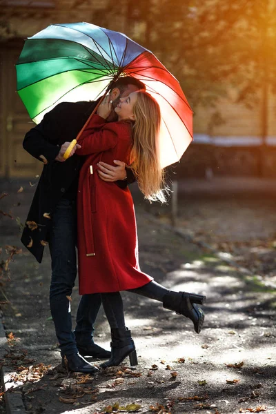 Junge Leute spazieren im Park unter buntem Regenschirm — Stockfoto