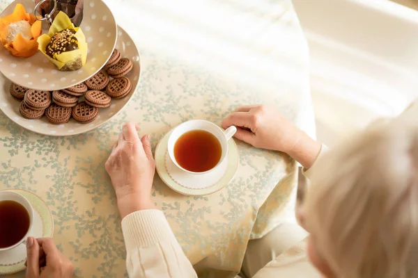 Seniorin hält heißen aromatischen Tee. Ansicht von oben — Stockfoto