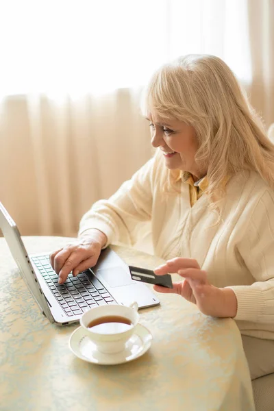 Femme âgée faisant des achats sur Internet tout en étant assis à la table — Photo