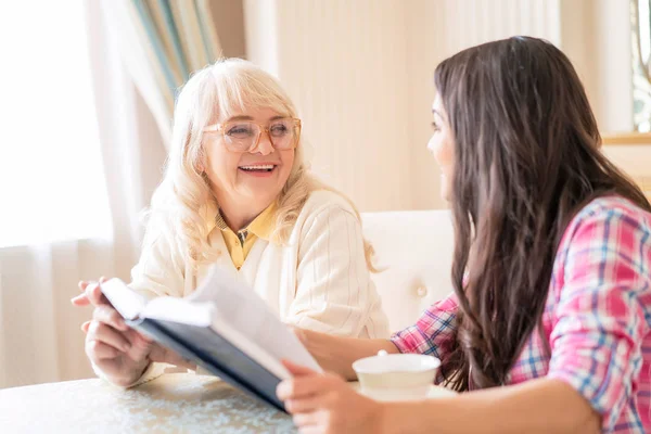 Senior moeder en dochter lezen een boek over een kopje thee — Stockfoto