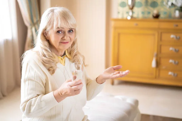 Старша жінка тримає таблетки і склянку води — стокове фото