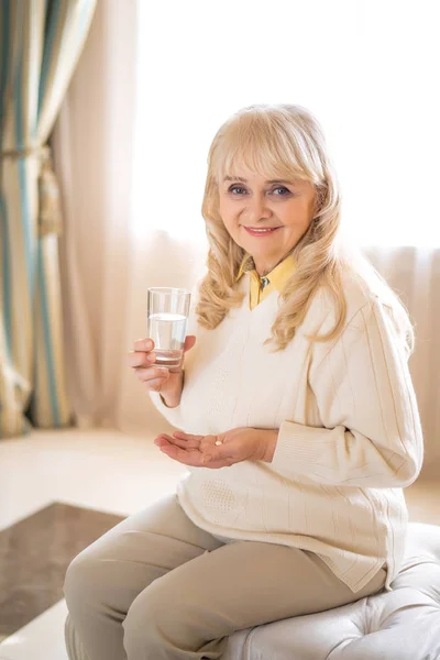 Seniorin hält Pillen und ein Glas Wasser in der Hand — Stockfoto
