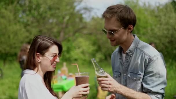 Šťastný chlap mluví s přítelkyní při pití na piknik v parku — Stock video