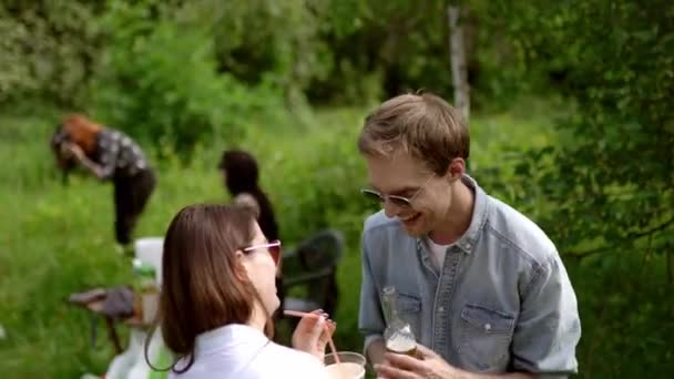 Boldog srác beszél barátnőjével, miközben ivás, piknik a parkban — Stock videók