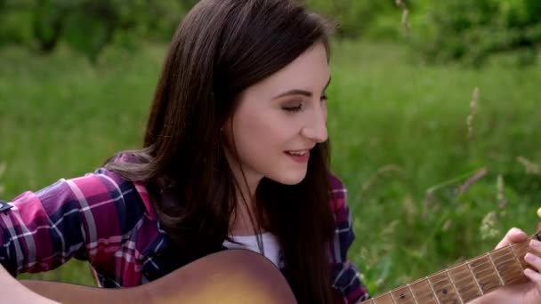 Músico femenino toca la guitarra en un día soleado afuera — Vídeos de Stock