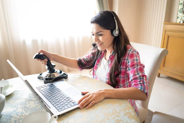 Pretty woman plays games with a retro joystick on laptop