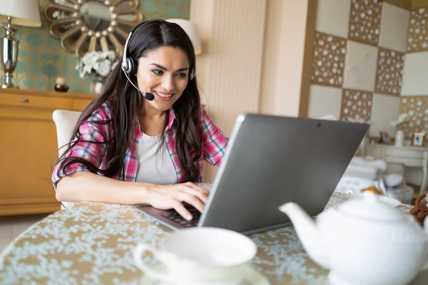 Piękna kobieta pracuje w jej laptopa, noszenie słuchawek — Zdjęcie stockowe