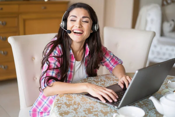 Bella donna lavora al suo computer portatile indossando cuffie — Foto Stock