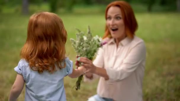 Bela criança dá flores à mãe sorridente — Vídeo de Stock