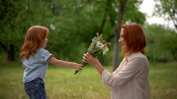 Красивый ребенок дарит цветы улыбающейся матери — стоковое видео