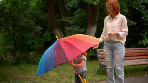 Happy mom and daughter under colored umbrella — Stock Video